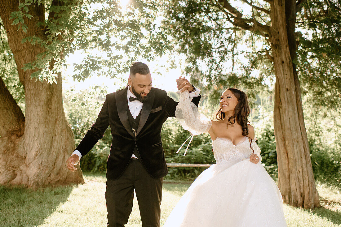 Smiling bride and groom dancing in park