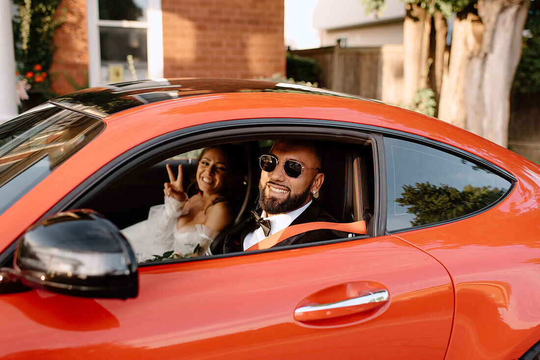 Smiling bride and groom in red car