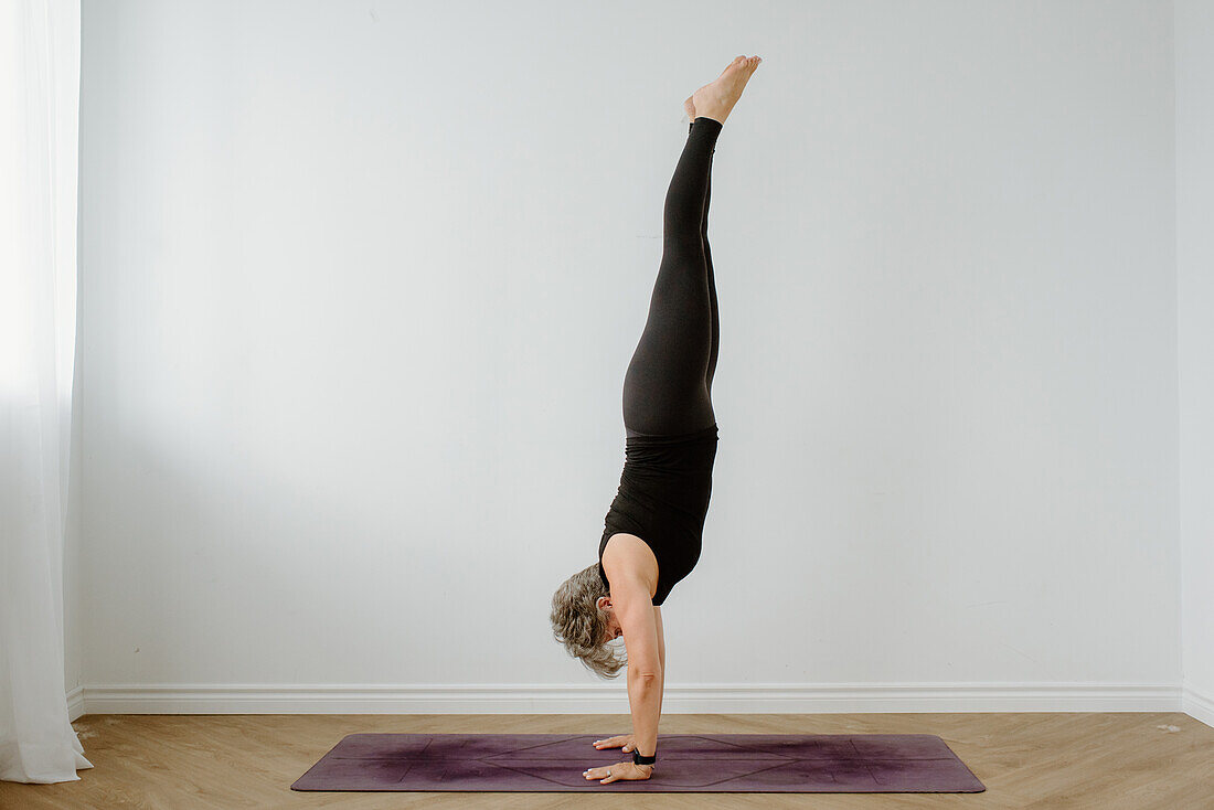 Woman performing handstand in room