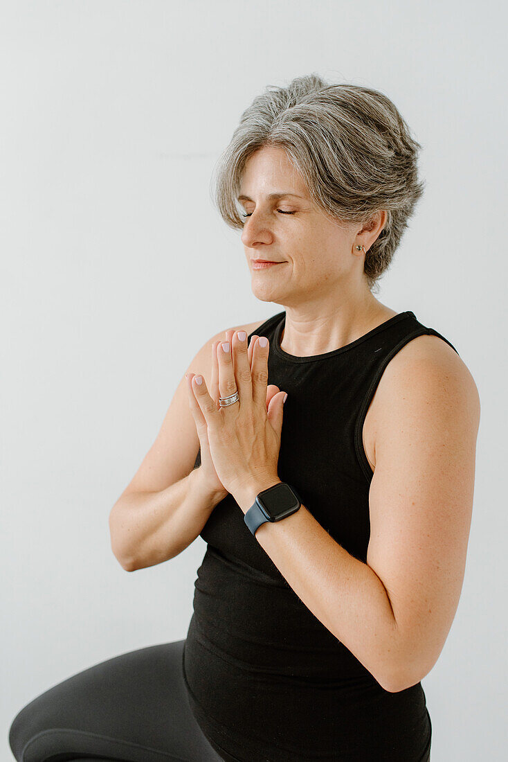 Studioaufnahme einer meditierenden Frau mit verschränkten Händen