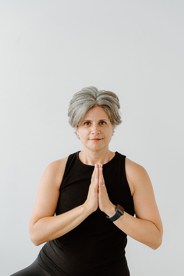 Studio shot of smiling woman with hands clasped