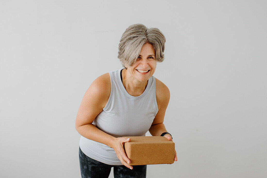 Portrait of smiling woman holding yoga block