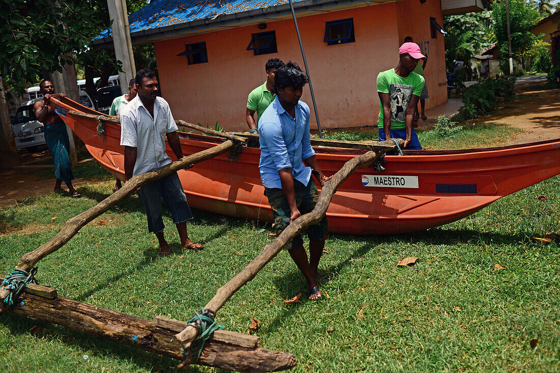 Gruppe von Menschen mit traditionellem Fischerboot in Weligama, Sri Lanka