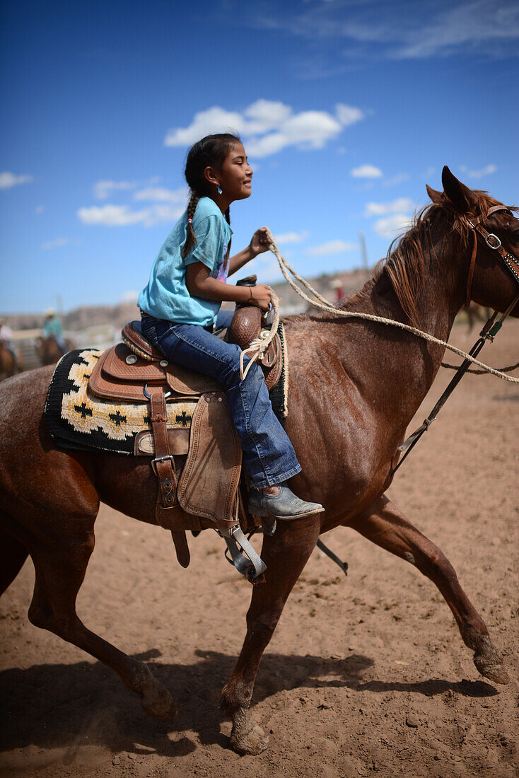 Cute young native american girl riding her horse during Navajo Nation Fair, a world-renowned event that showcases Navajo Agriculture, Fine Arts and Crafts, with the promotion and preservation of the Navajo heritage by providing cultural entertainment. Window Rock, Arizona.