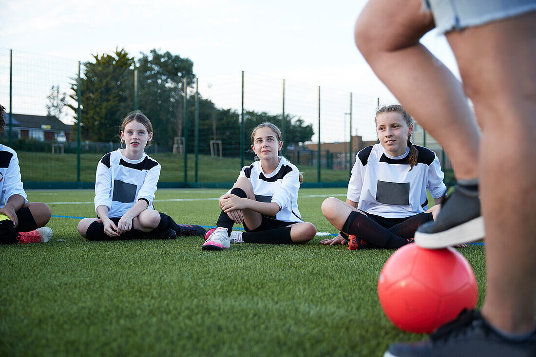 UK, Female soccer team (10-11, 12-13) sitting in field during training