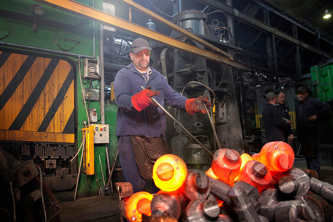 A clipped crank shaft is swung out in a pair of tongs from the clipping press into a steel container