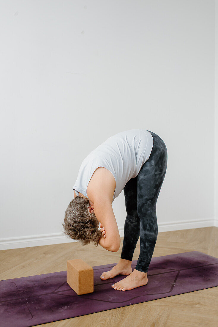 Frau übt Yoga mit Yogablock auf einer Übungsmatte