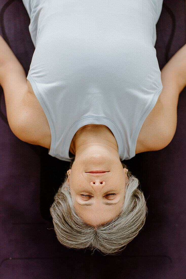 Overhead view of woman lying on yoga mat
