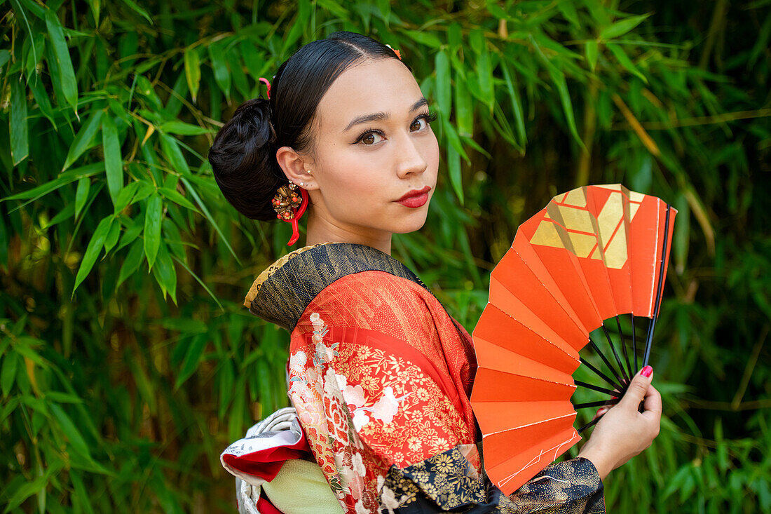 Portrait of woman wearing kimono and holding fan