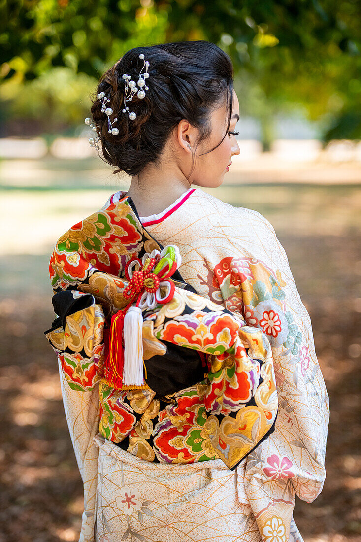 Rear view of woman wearing kimono standing in park