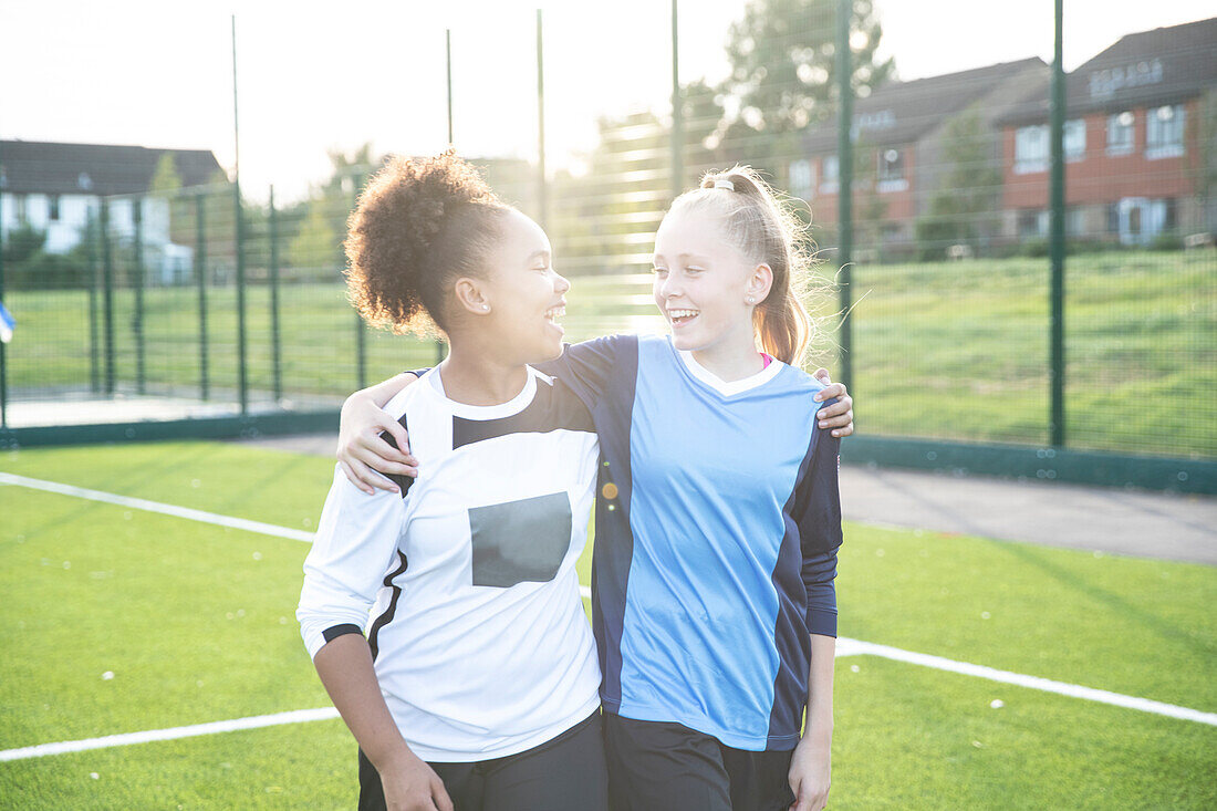 UK, Smiling female soccer team members (12-13) embracing in field