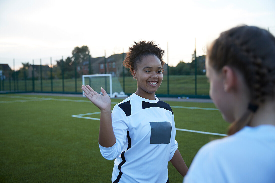 UK, Weibliche Fußballspielerinnen (10-11, 12-13) geben High Five auf dem Feld