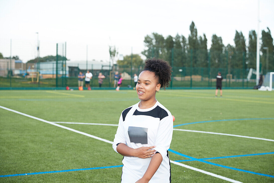 UK, Smiling female soccer player (12-13) in soccer field