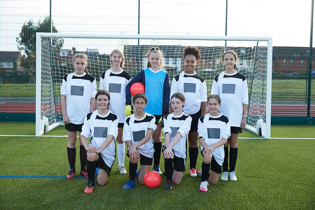UK, Gruppenporträt einer Mädchenfußballmannschaft (10-11, 12-13) vor einem Tor