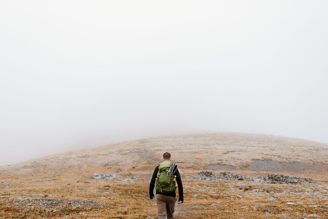 Kanada, Yukon, Whitehorse, Rückansicht eines Mannes beim Wandern in einer nebligen Landschaft
