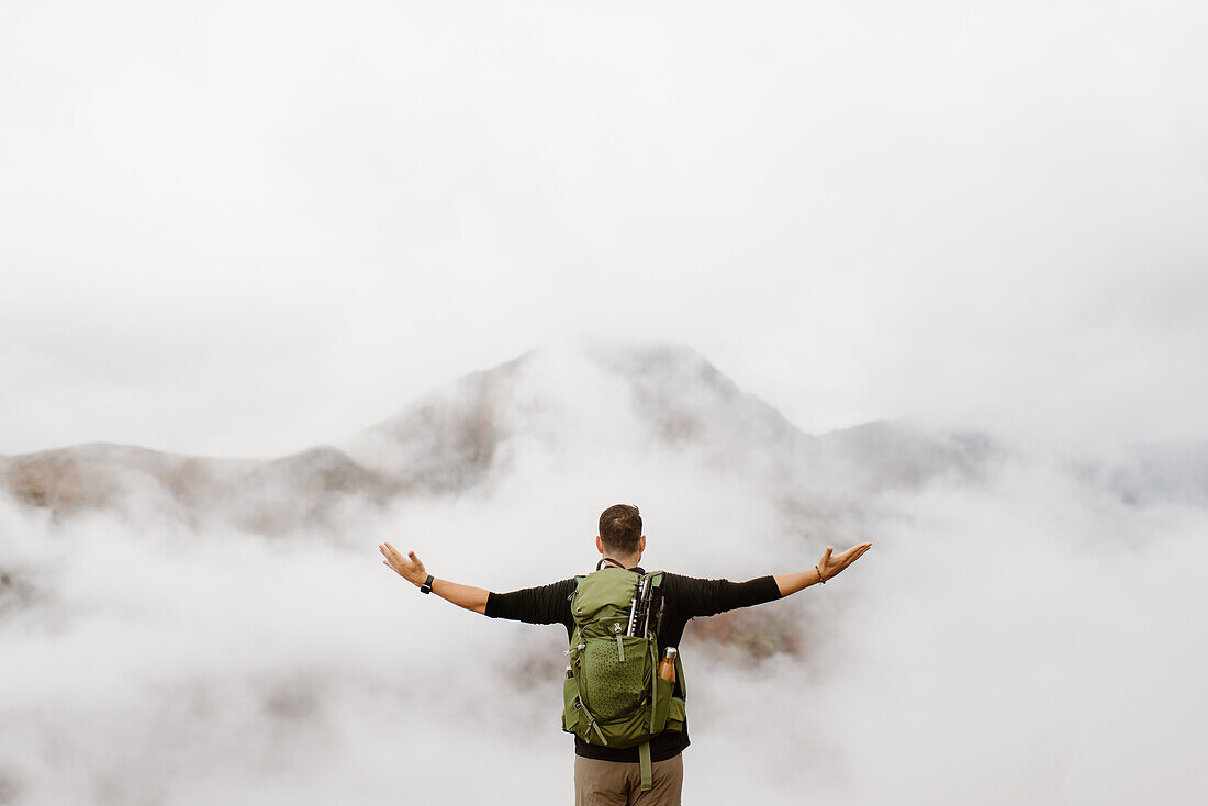 Canada, Whitehorse, Rear view of man with arms raised in foggy landscape