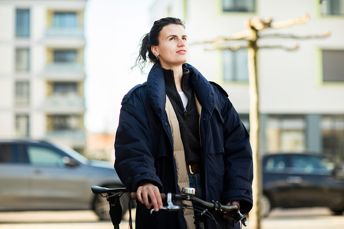 Frau mit Fahrrad in der Stadt stehend