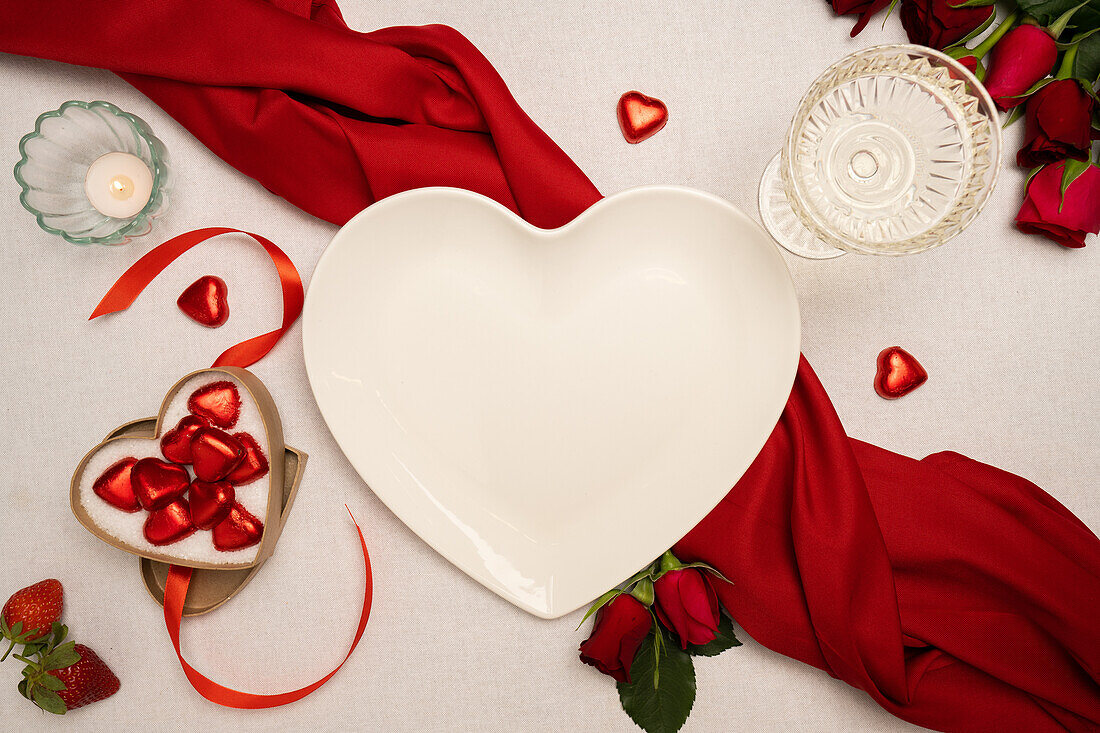 Herzförmiger Teller und Valentinstagsdekoration auf dem Tisch
