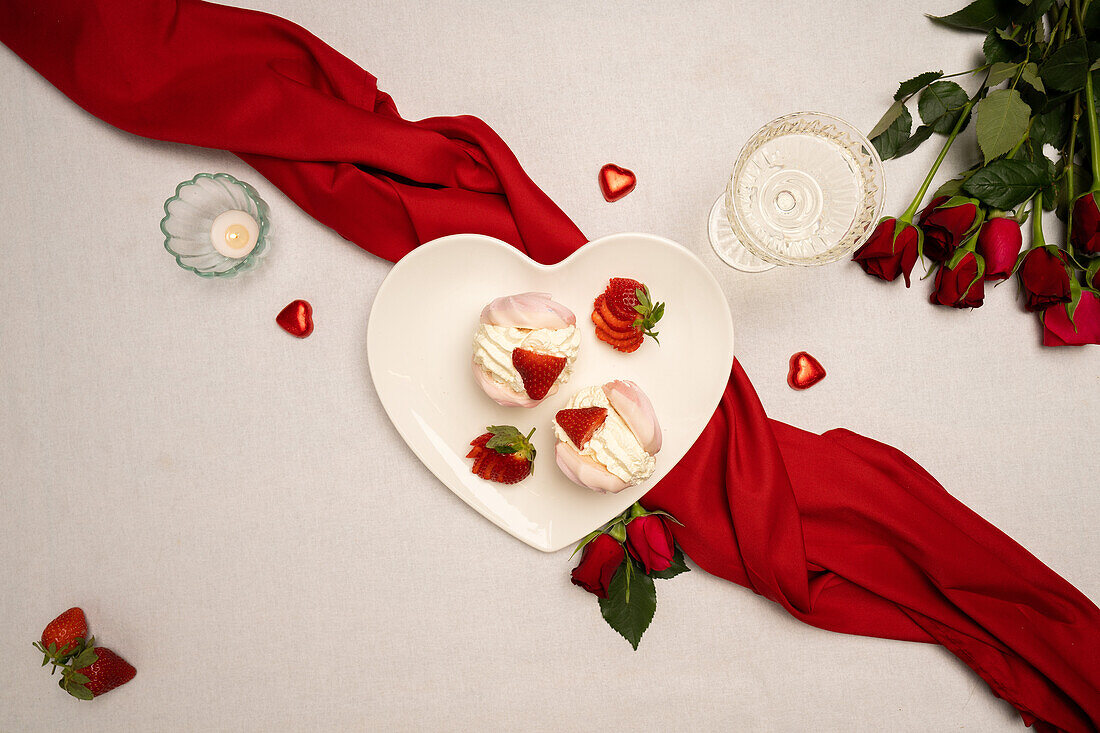 Heart-shapedÊplate with meringueÊand Valentines Day decorations on table