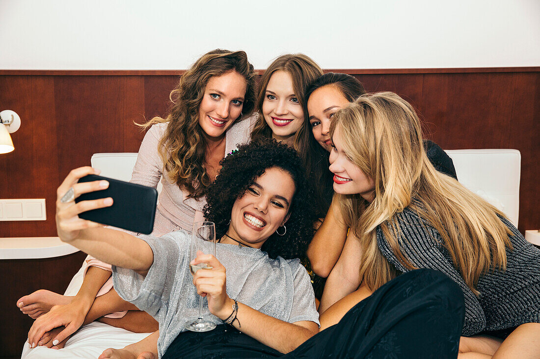 Fünf junge Frauen machen ein Selfie auf dem Bett
