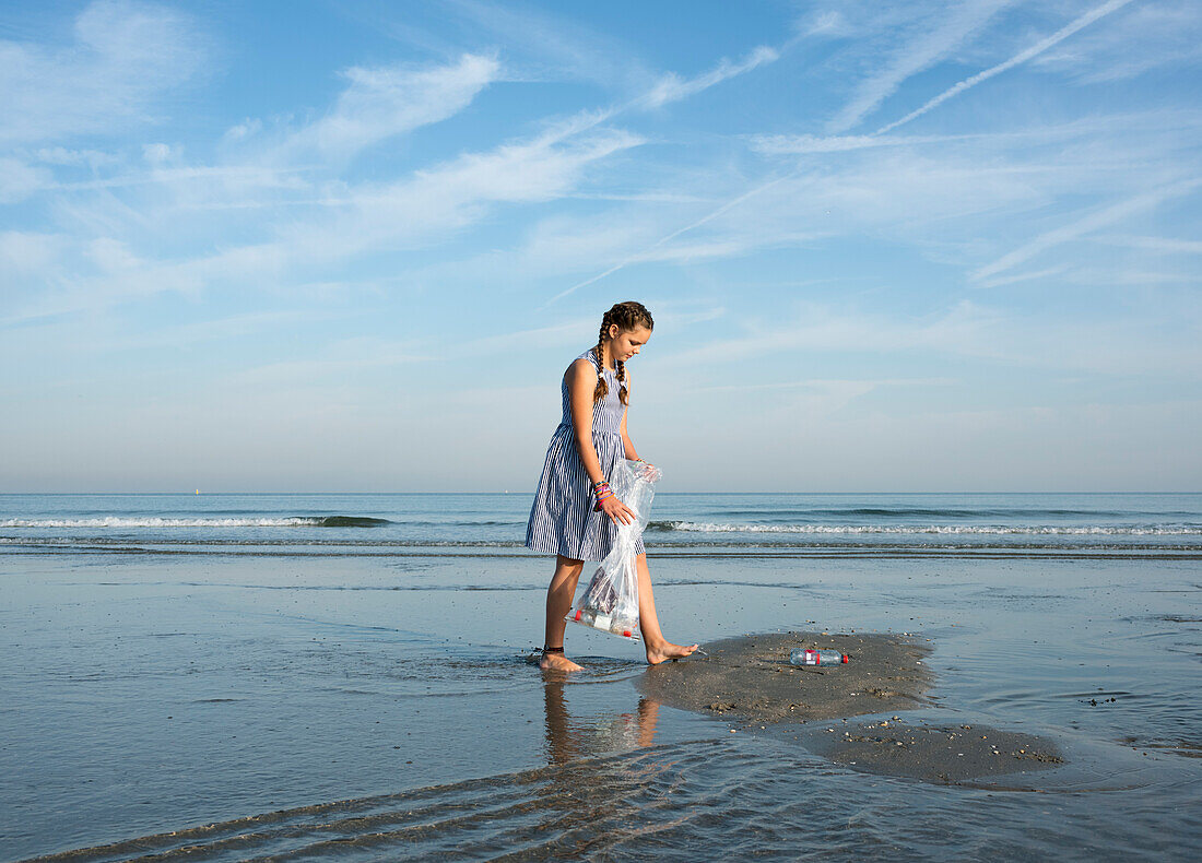 Mädchen sammelt Plastikmüll vom Strand auf, Hoek van Holland, Niederlande