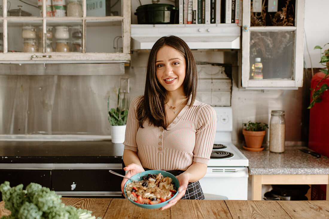 Smiling young woman holding granola bowl