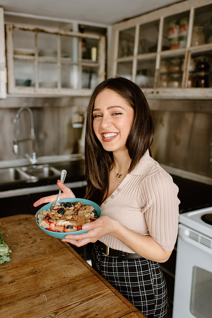 Smiling young woman holding granola bowl