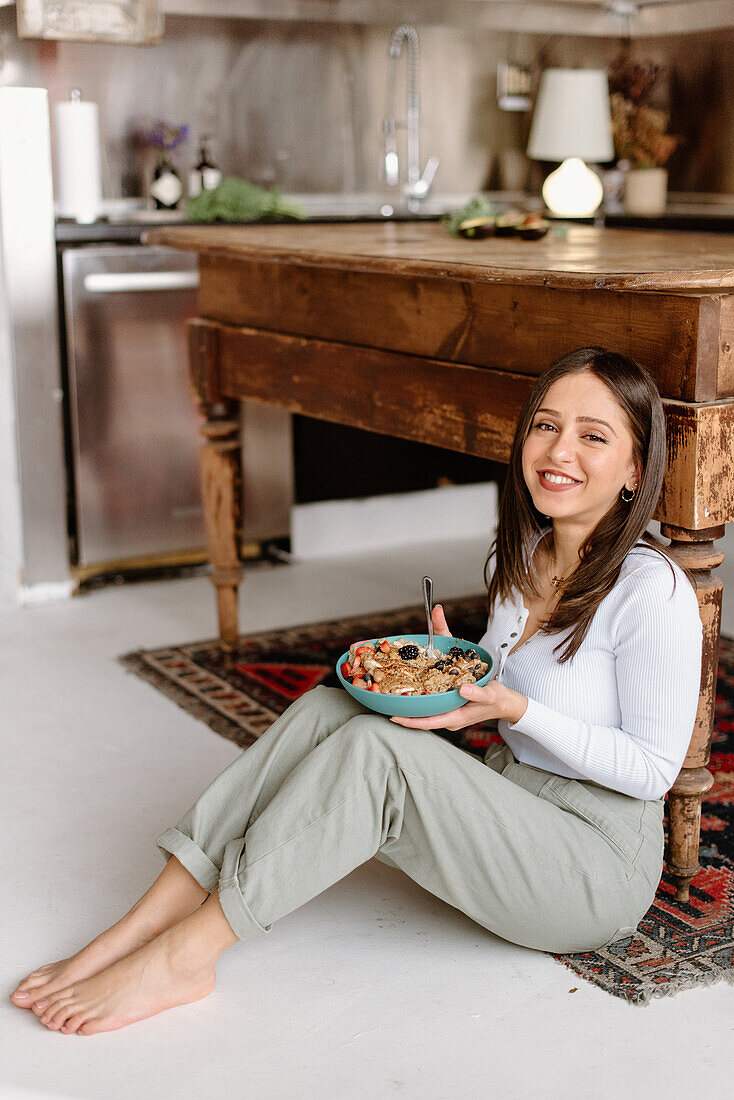 Smiling young woman holding granola bowl