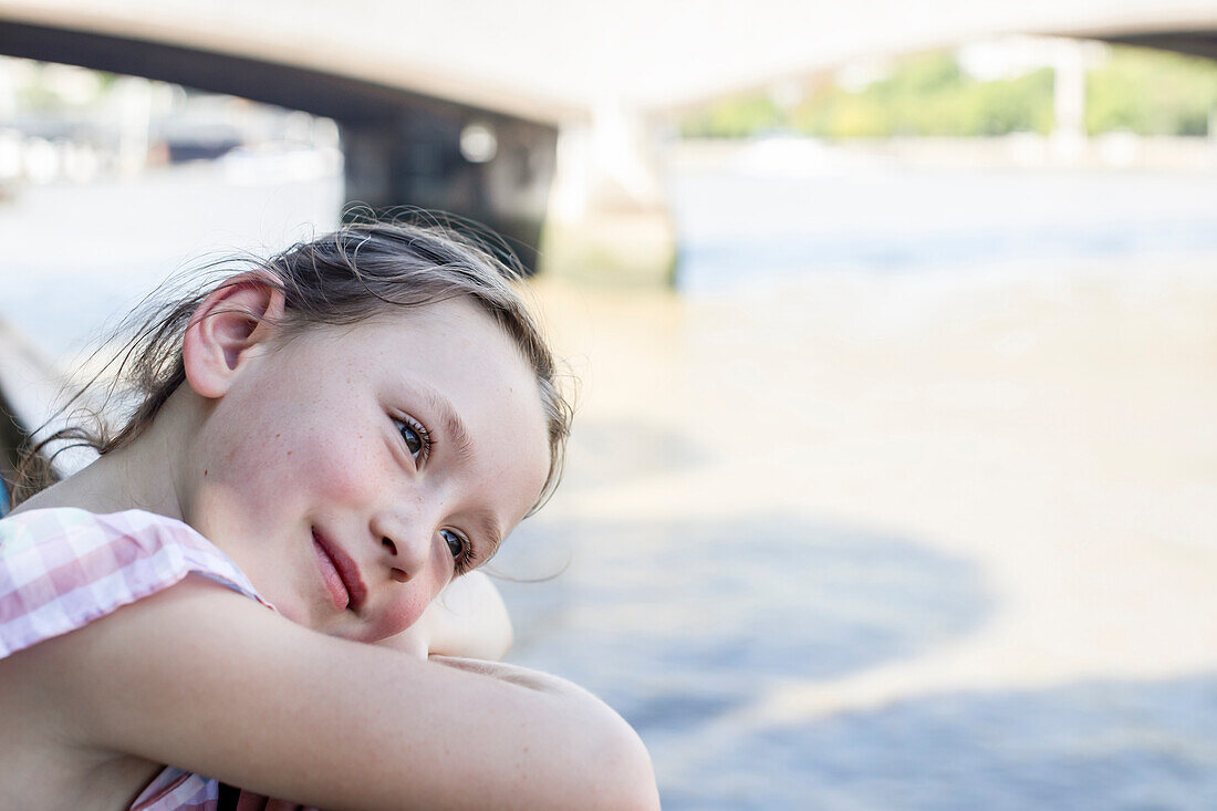 Close-up of smiling girl (4-5) leaning on fence