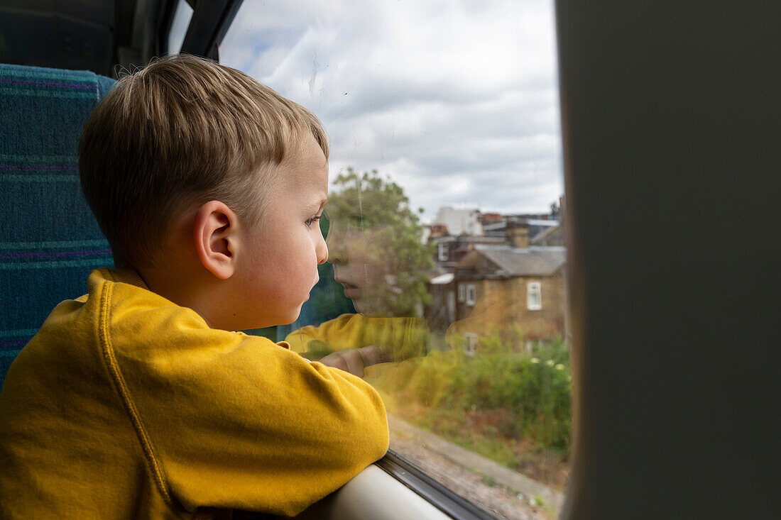 Junge (18-23 Monate) schaut durch ein Fenster im Zug
