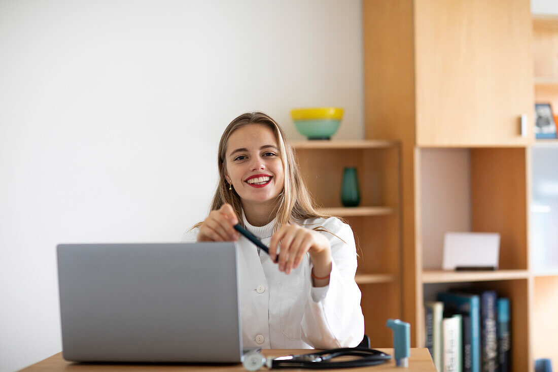 Portrait of smiling young female doctor with laptop