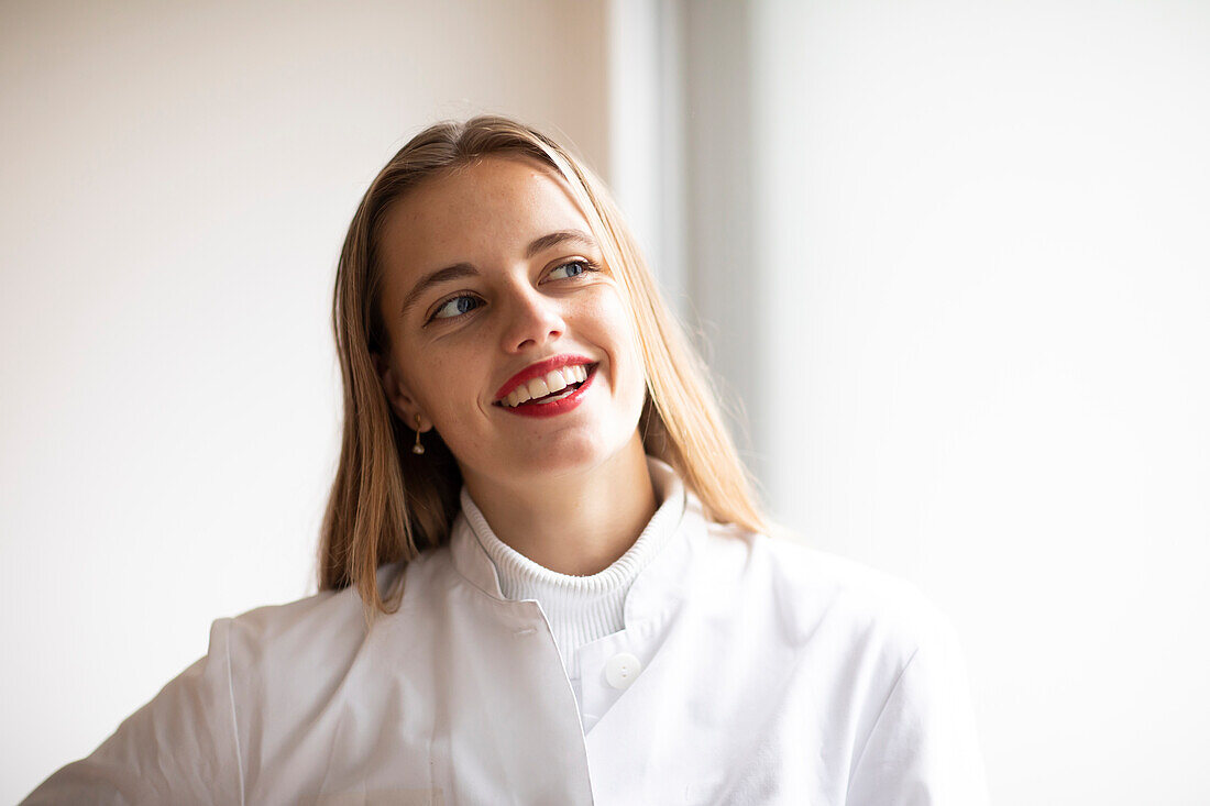 Portrait of smiling young woman in lab coat