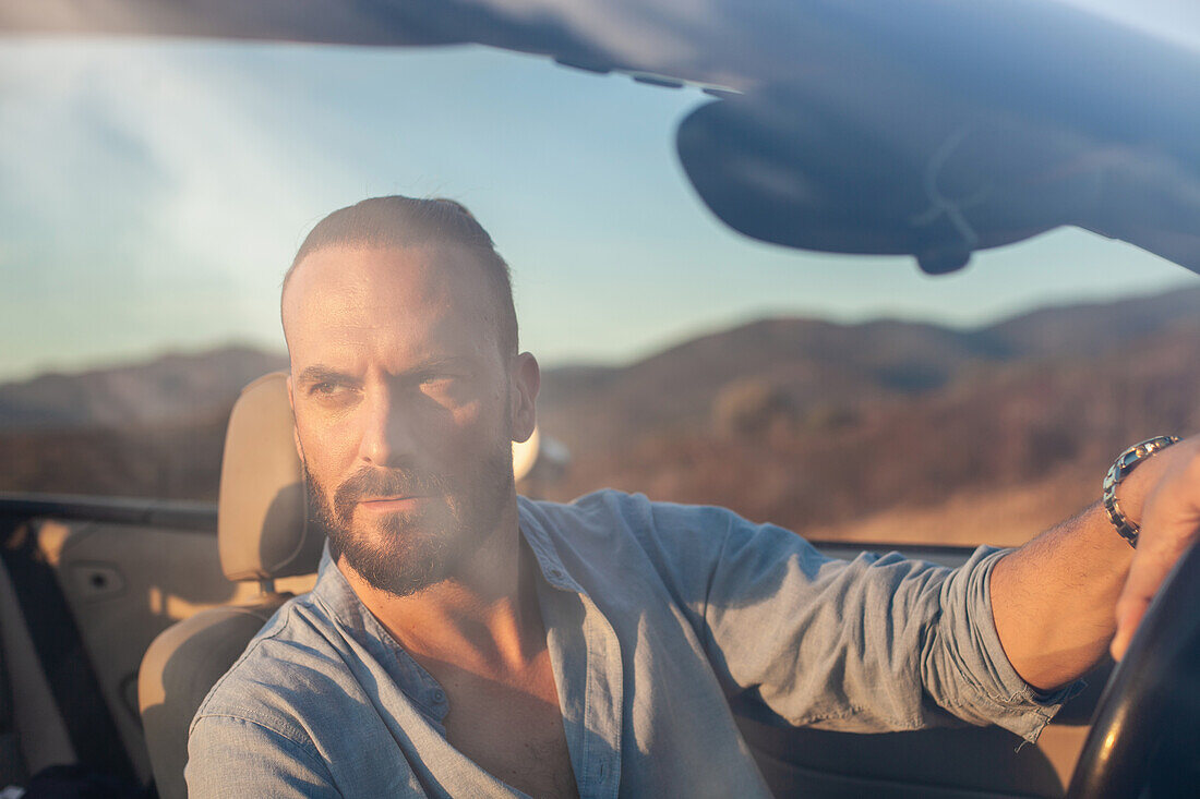 Man driving convertible car in landscape