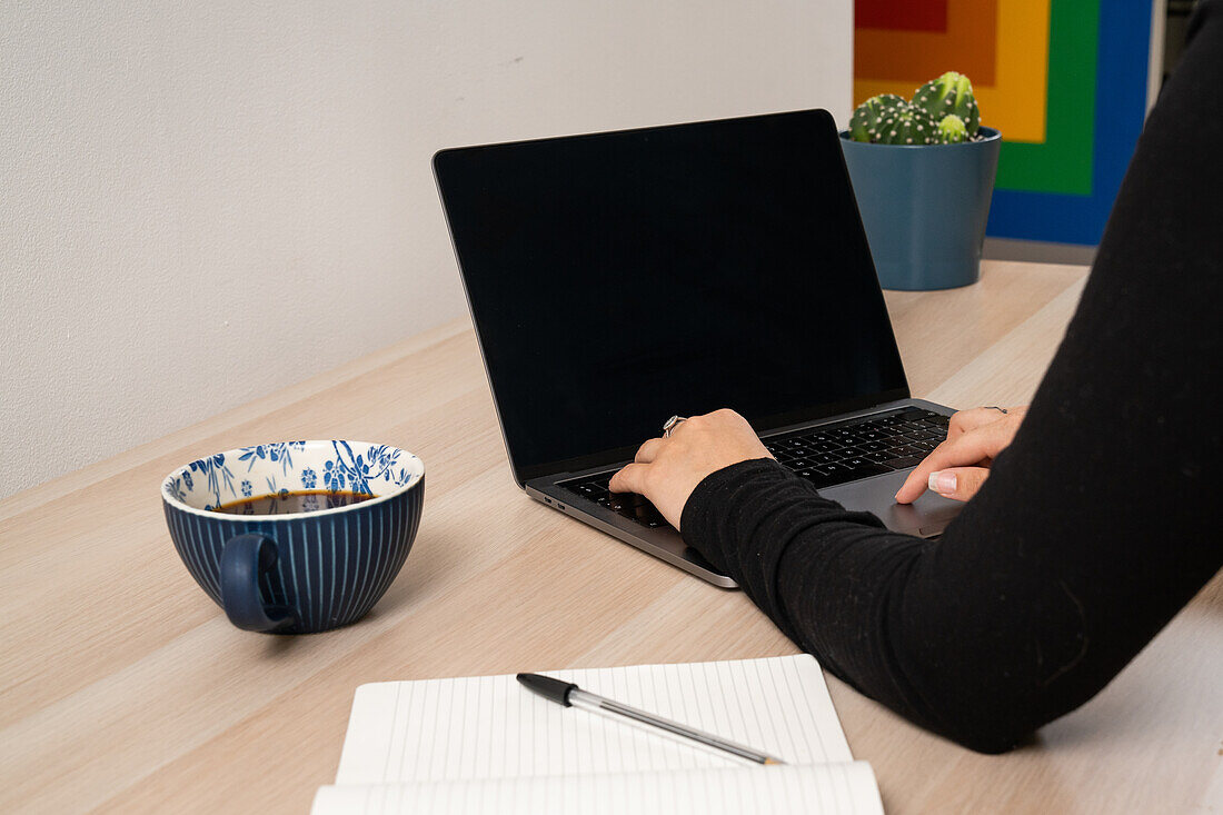 Close-up of hands of using laptop at desk