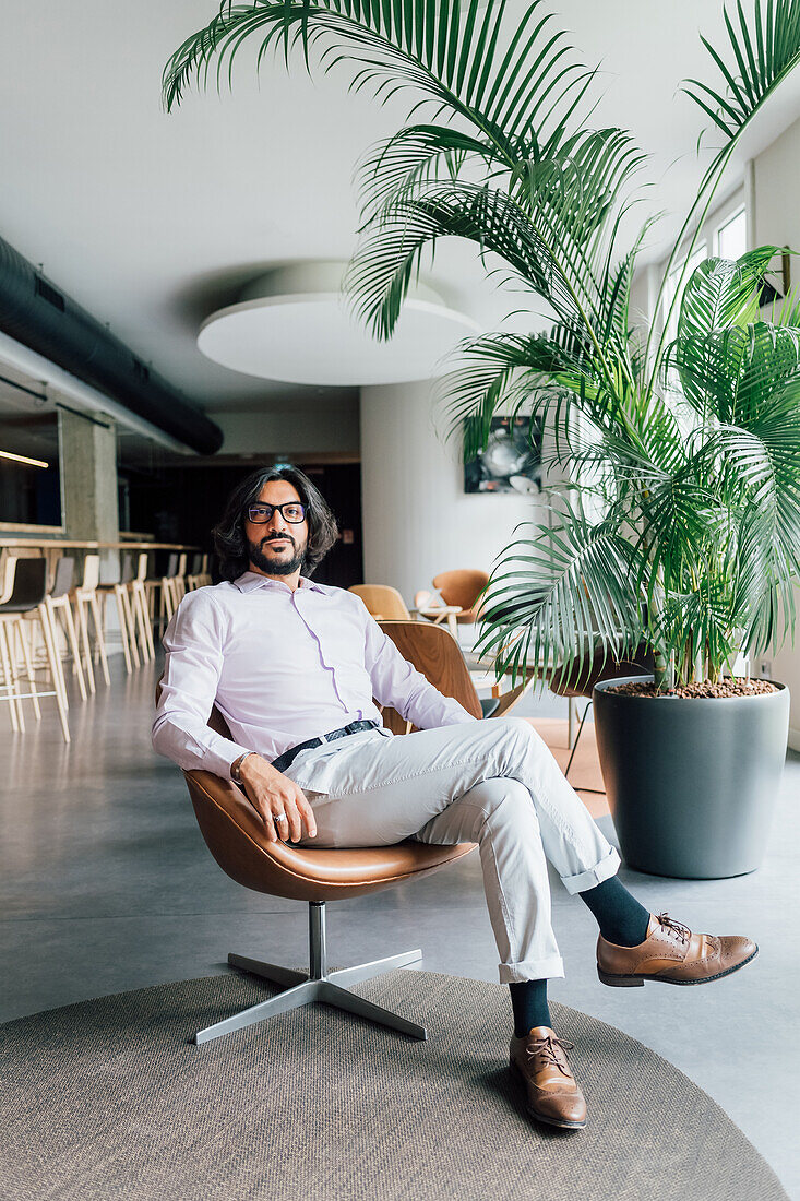 Italy, Portrait of man sitting in armchair in creative studio