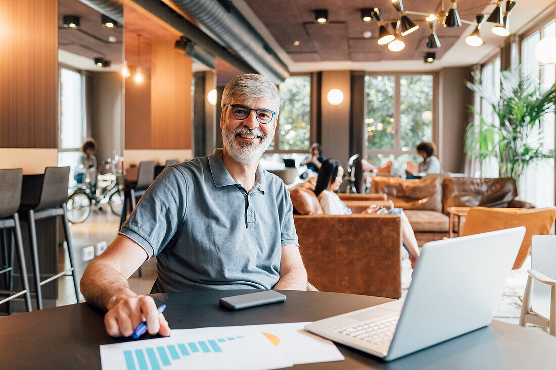 Italy, Portrait of smiling man working at table in creative studio