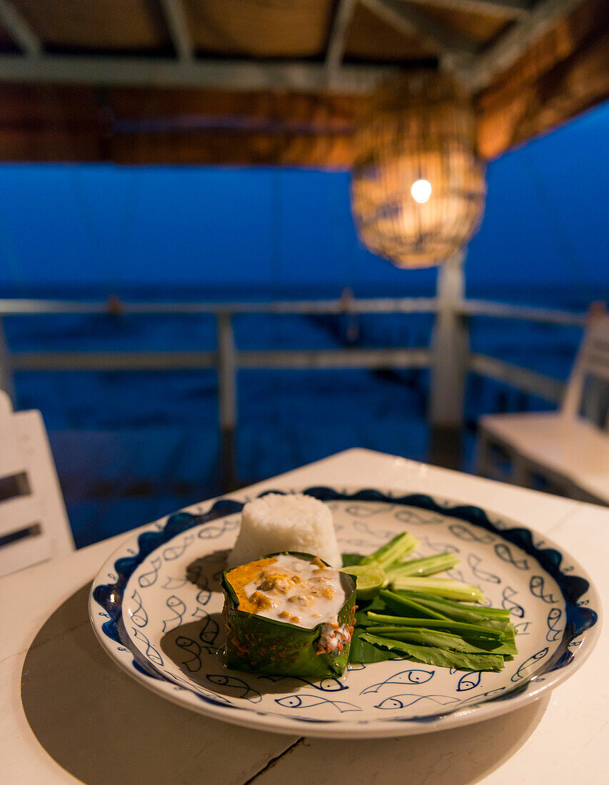 Cambodia, Kep, Fish amok on plate at Sailing Club at dusk