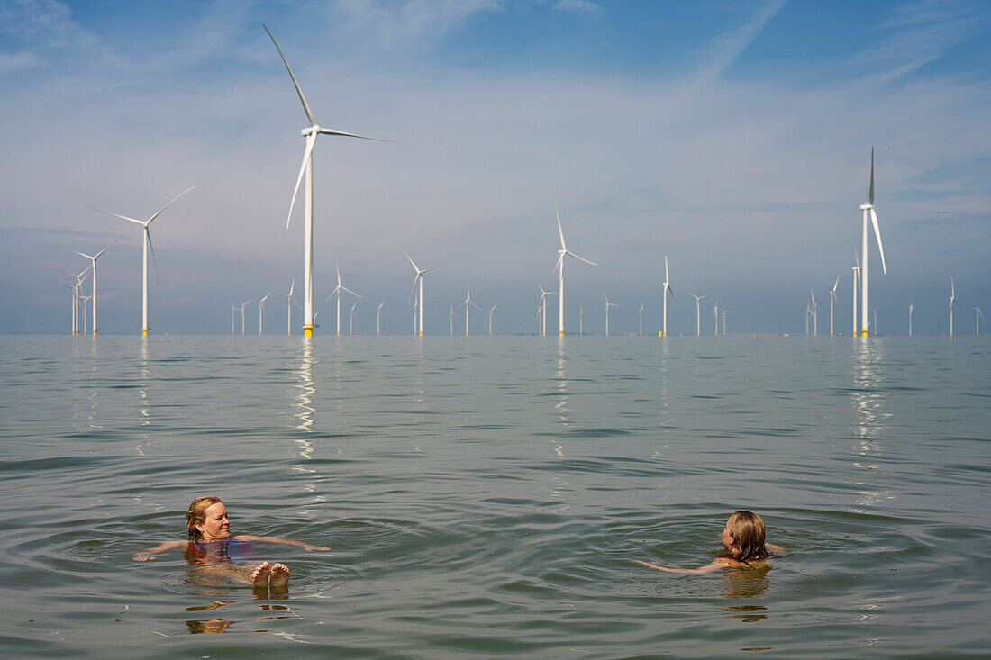 Niederlande, Friesland, Breezanddijk, Frau und Mädchen schwimmen in der Nähe von Windkraftanlagen