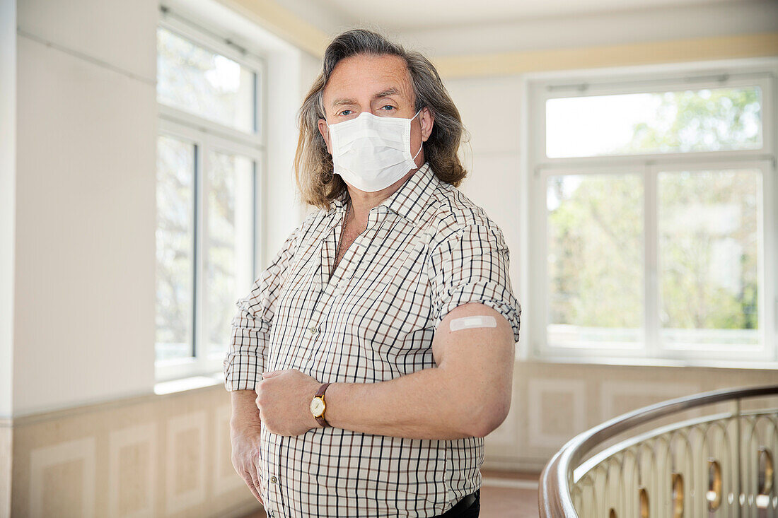 Österreich, Porträt eines Mannes mit Gesichtsmaske und Klebeverband am Arm