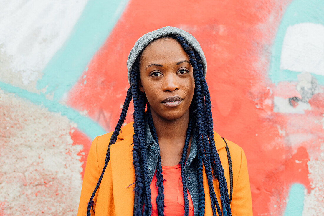 Italy, Milan, Portrait of young woman against graffiti covered wall