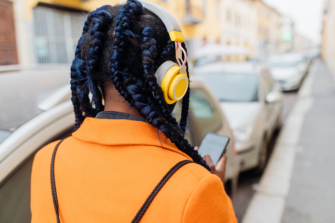 Italy, Milan, Rear view of woman with braided hair and headphones