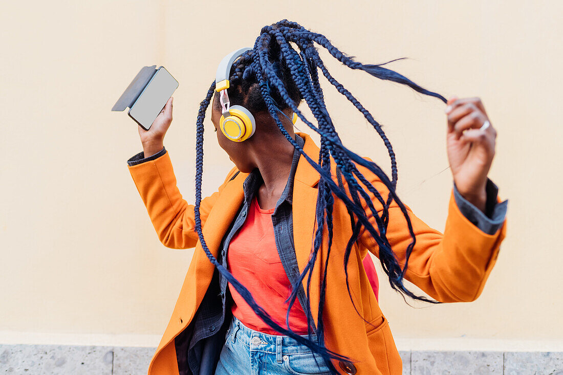 Italy, Milan, Woman with headphones and smart phone dancing outdoors