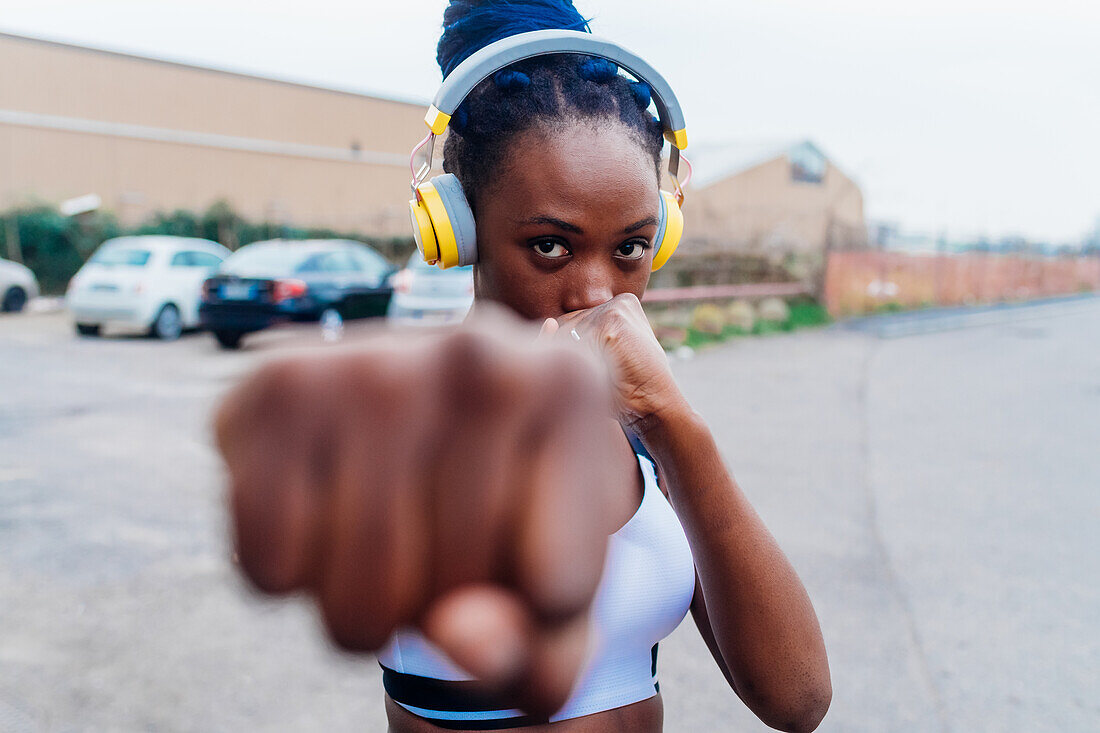 Italy, Milan, Woman with headphones punching the air in city