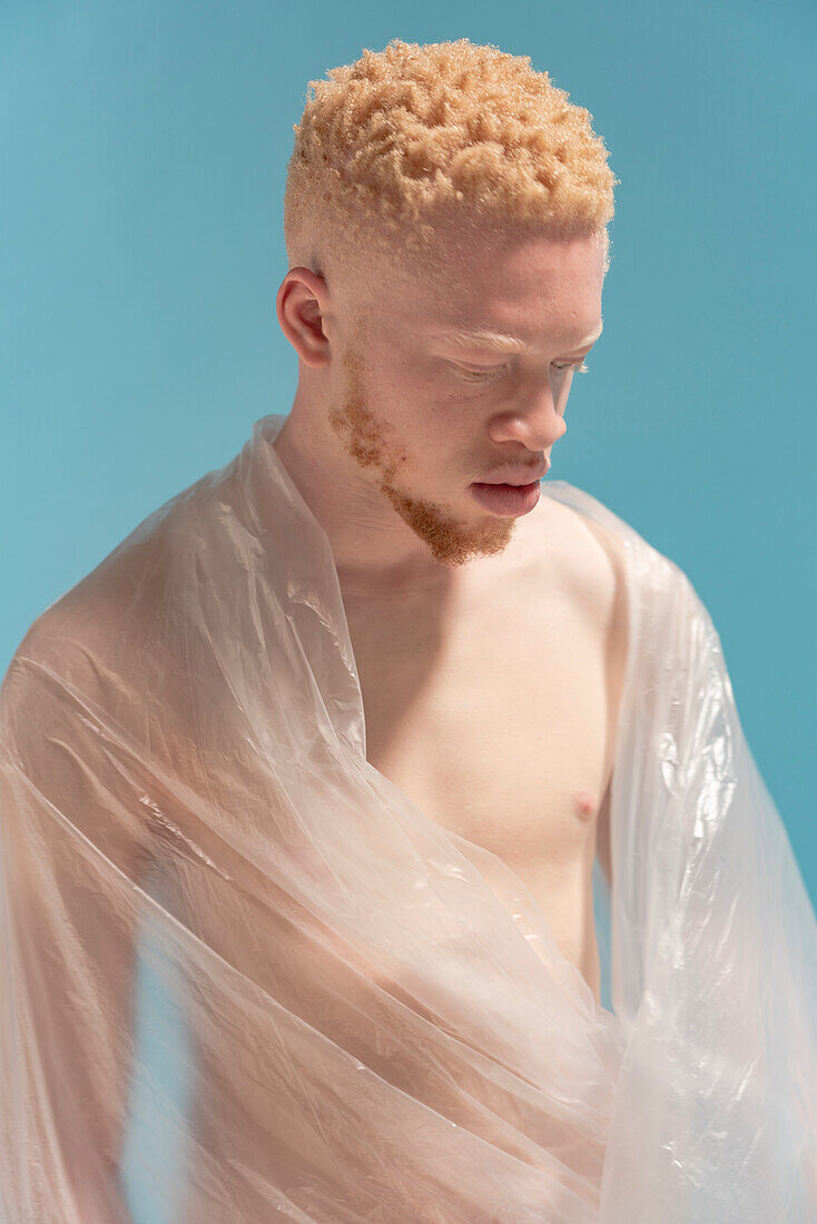 Studio-Porträt eines in Plastikfolie eingewickelten Albino-Mannes ohne Hemd