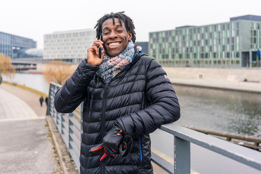 Germany, Berlin, Smiling man using smart phone in city