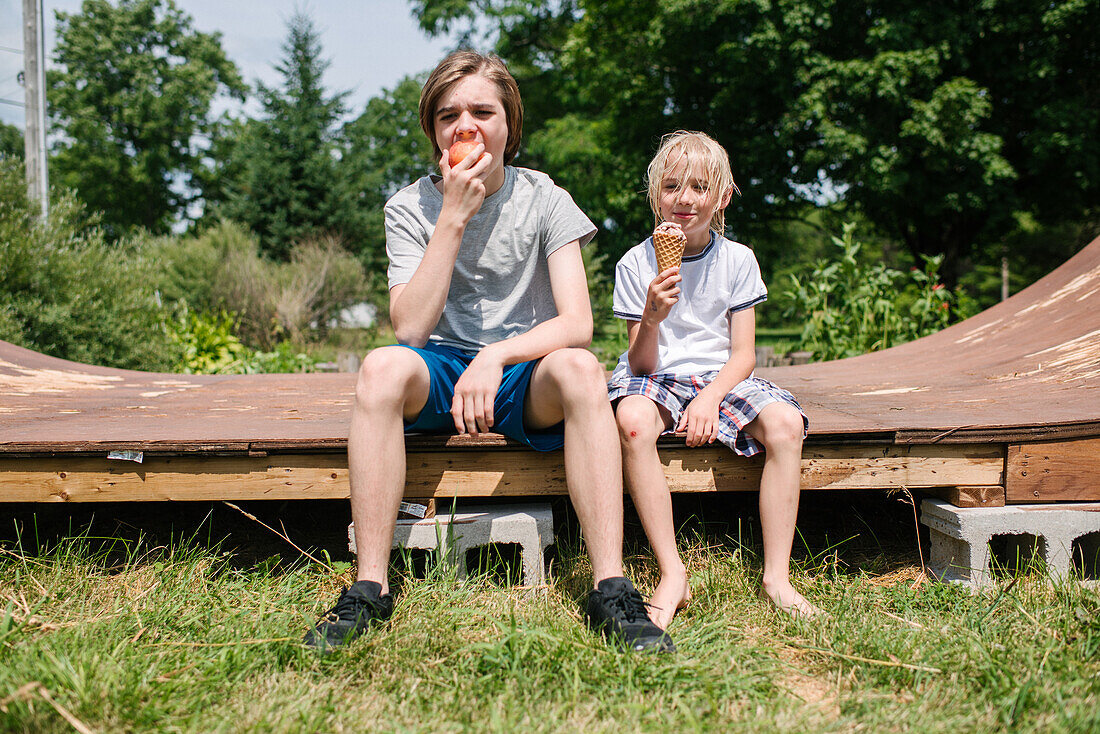 Canada, Ontario, Kingston, Boys (8-9, 14-15) eating ice cream and apple
