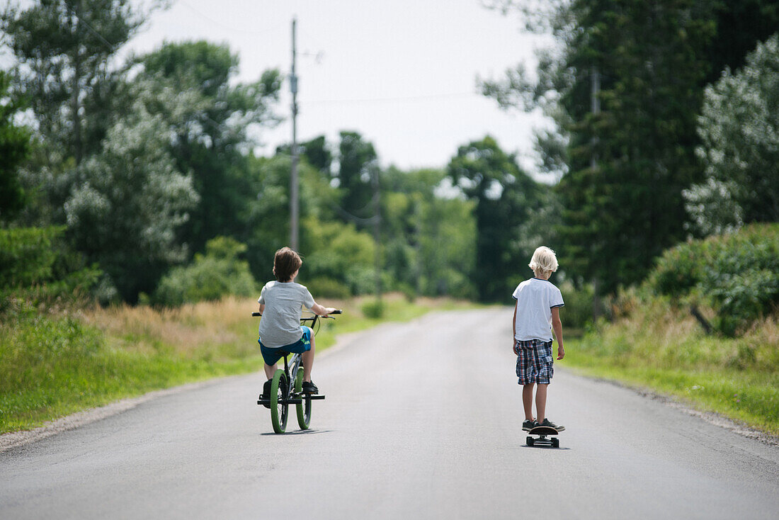 Kanada, Ontario, Kingston, Jungen (8-9, 14-15) beim Fahrradfahren und Skateboarden
