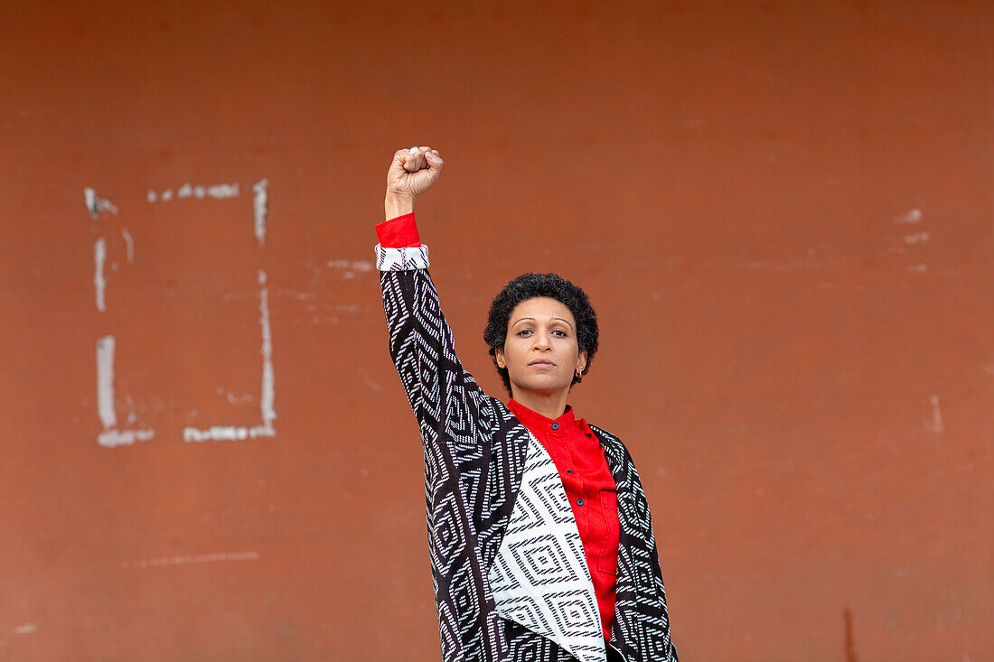 Italy, Tuscany, Pistoia, Woman standing against wall and raising fist