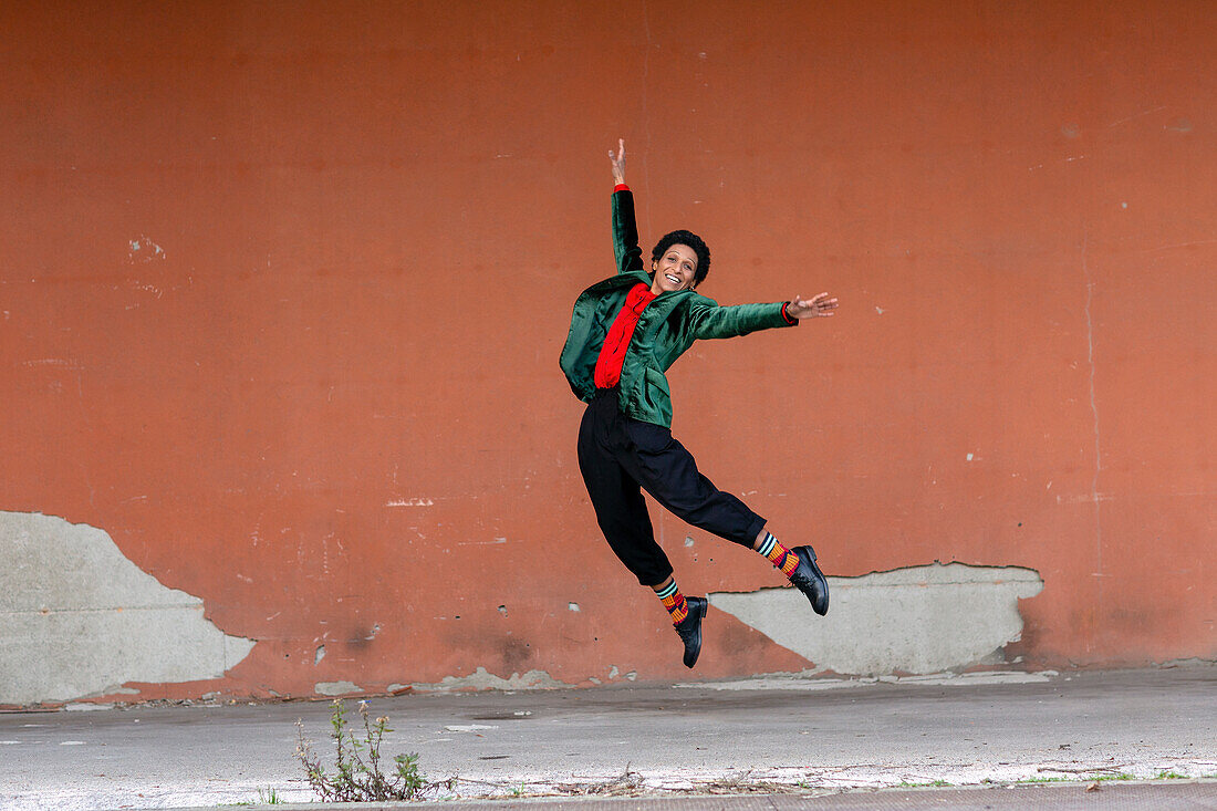 Italien, Toskana, Pistoia, Lächelnde Frau, die gegen die Wand springt