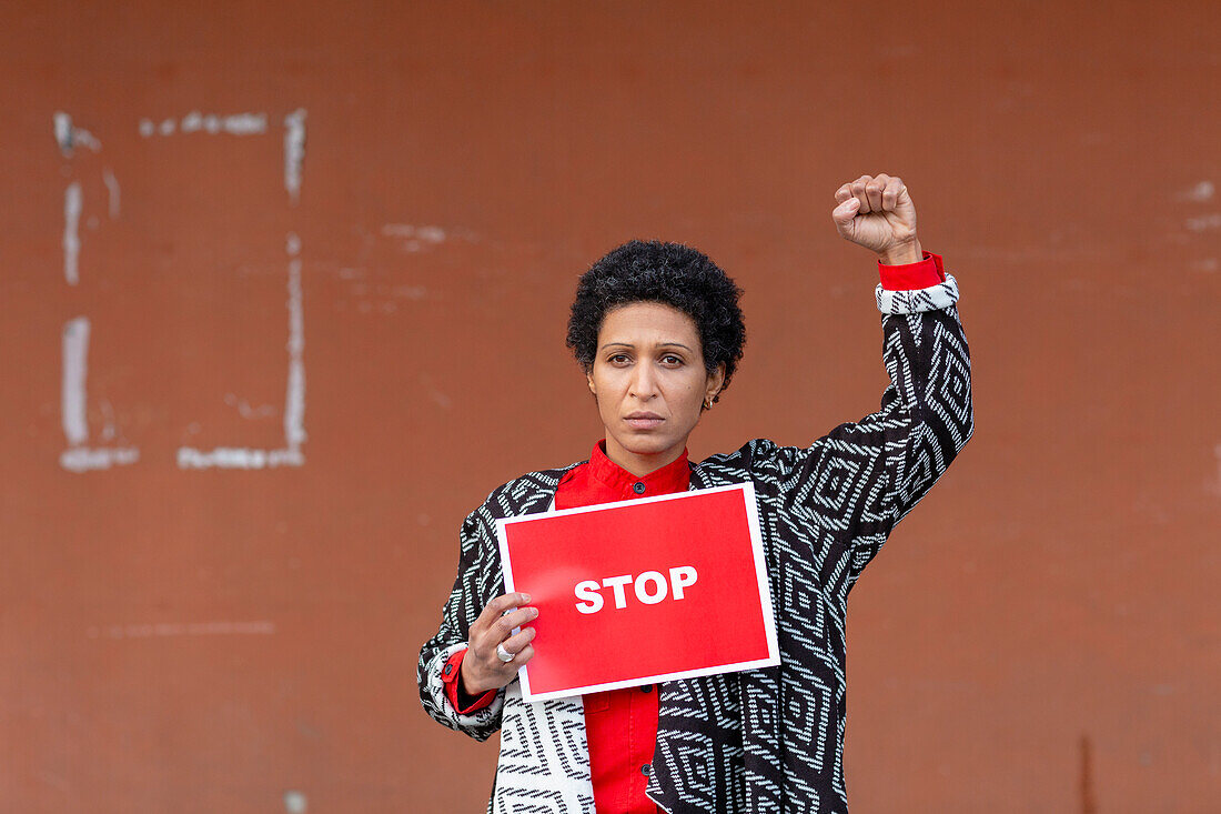 Italy, Tuscany, Pistoia, Woman holding stop sign and raising fist